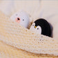 Penguin and polar bear USB Rechargeable Hand Warmers tucked under a blanket, offering warmth for camping and hiking.