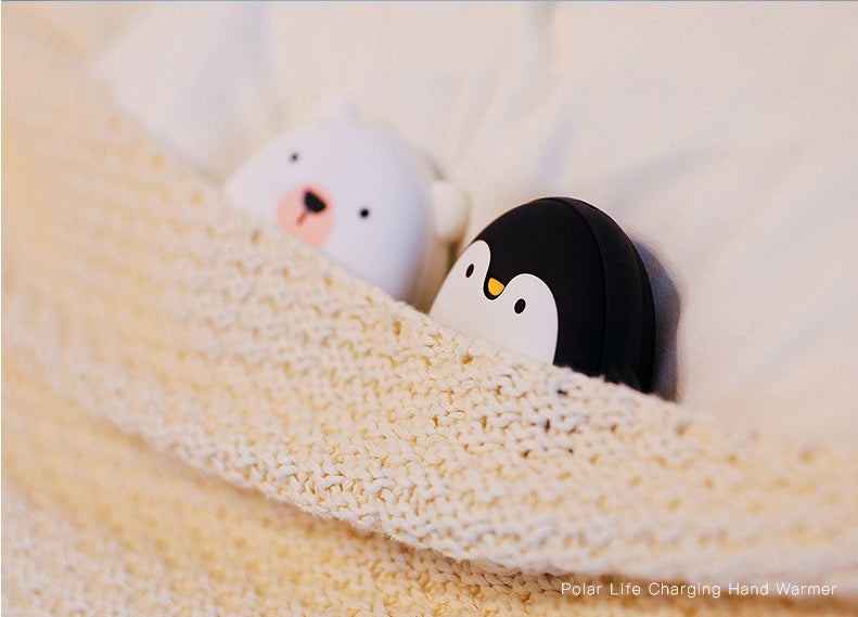 Penguin and polar bear USB Rechargeable Hand Warmers tucked under a blanket, offering warmth for camping and hiking.