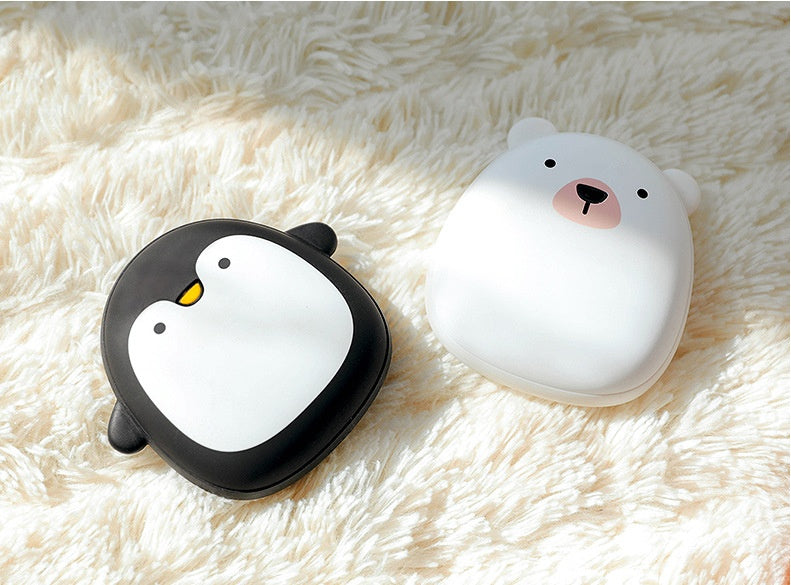 Penguin and polar bear USB Rechargeable Hand Warmers lying on a soft rug, ideal for cold weather outdoor adventures.