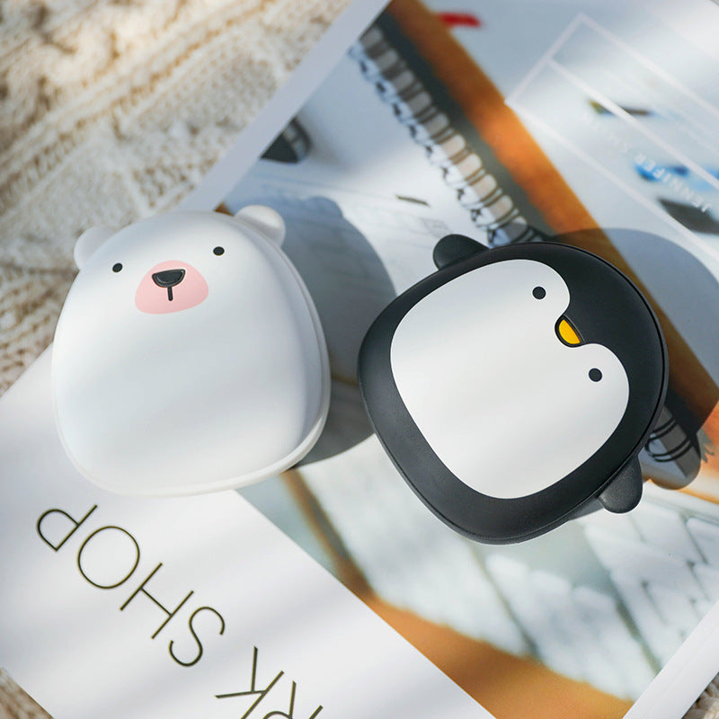 Polar bear and penguin USB Rechargeable Hand Warmers placed on a magazine, stylish and practical for hiking and camping.