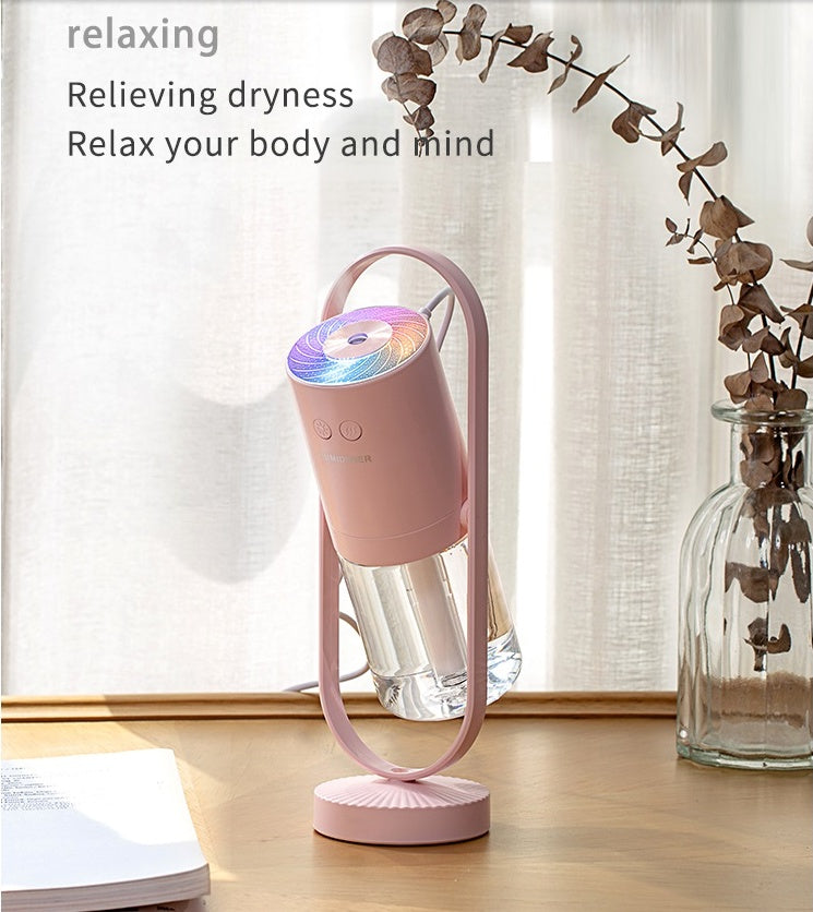 Pink USB Mini Humidifier on wooden table emitting mist, promoting relaxation and moisture for a healthier indoor environment.