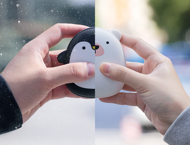 Hands holding USB Rechargeable Hand Warmers shaped like a penguin and polar bear, ideal for outdoor recreation warmth.