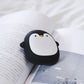 Penguin-shaped USB Rechargeable Hand Warmer resting on an open book, combining warmth and adorable design for camping use.