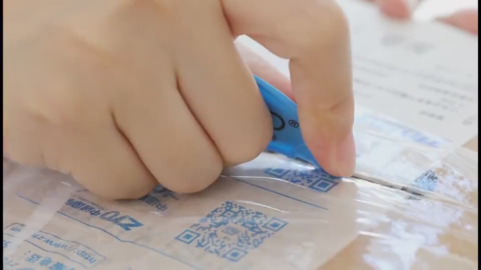 Close-up of hand opening a package with a cutter, possibly unboxing USB Rechargeable Hand Warmers for outdoor use.